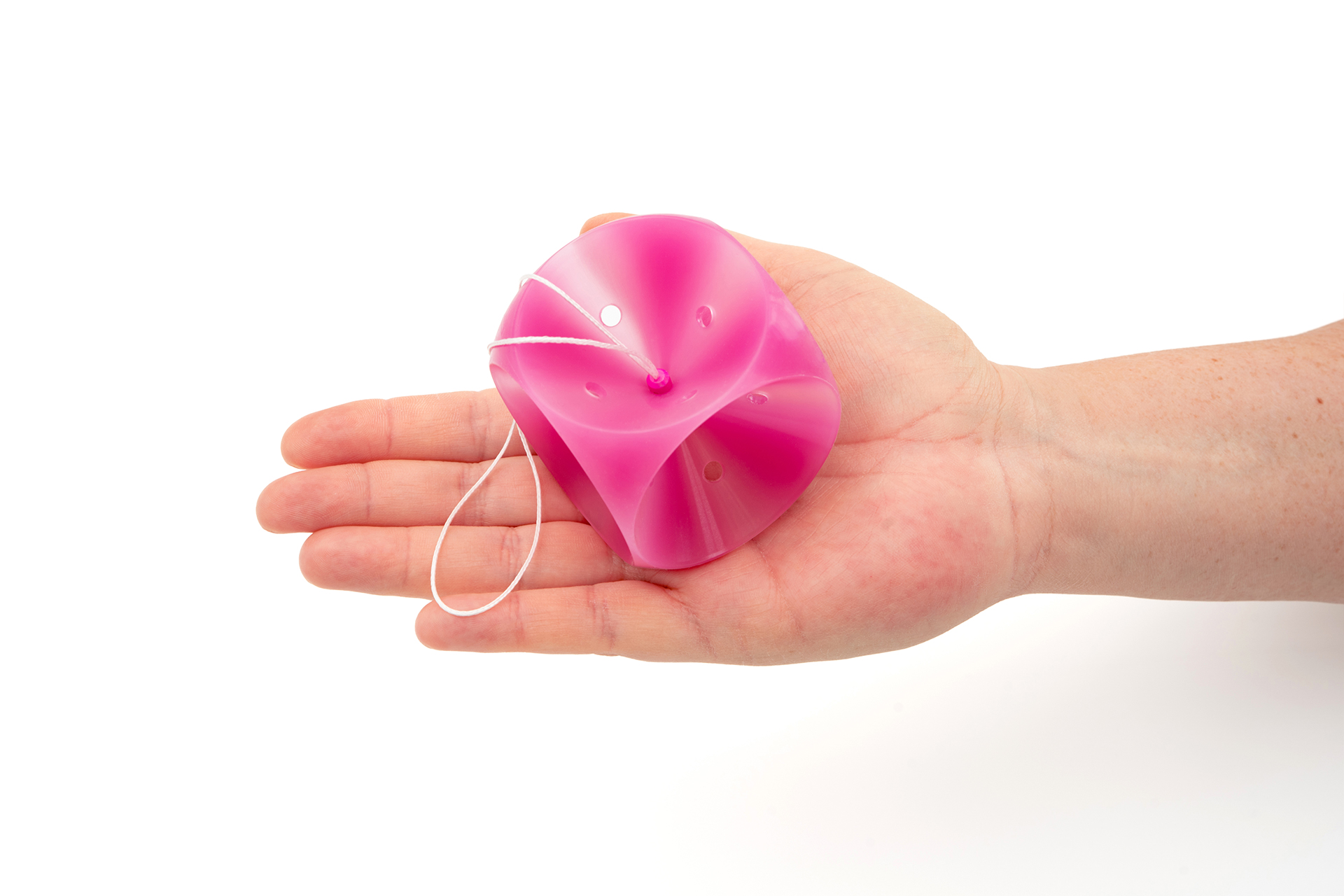 Ein pinkes femicare Würfel-Pessar mit Perforation der Größe 75 liegt in einer ausgestreckten Hand.